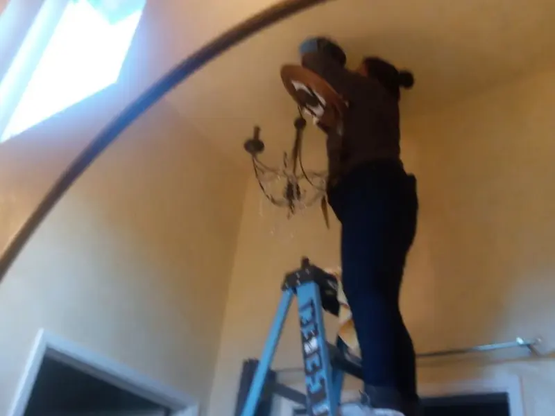 Electrician installing a chandelier in a Lincoln Park residence